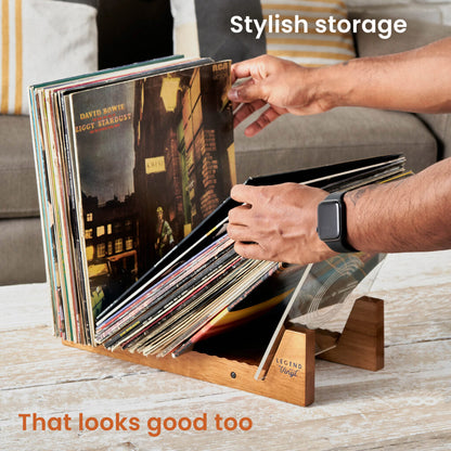 Hands browsing records stored upright in the oak display shelf